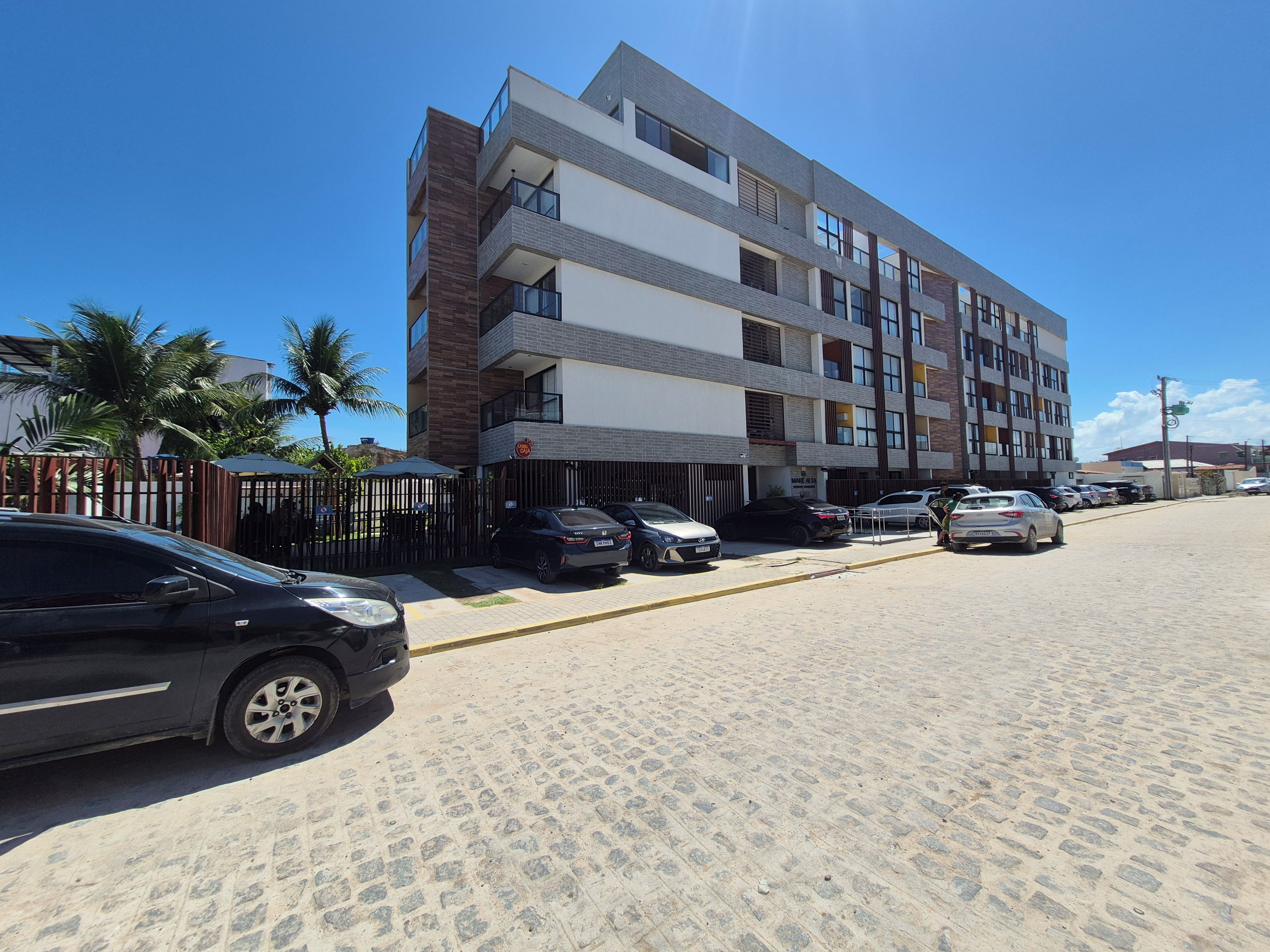 Um edifício com vários andares e uma área de estacionamento na frente.