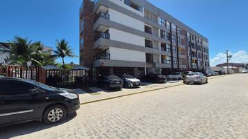 Um edifício com vários andares e uma área de estacionamento na frente.