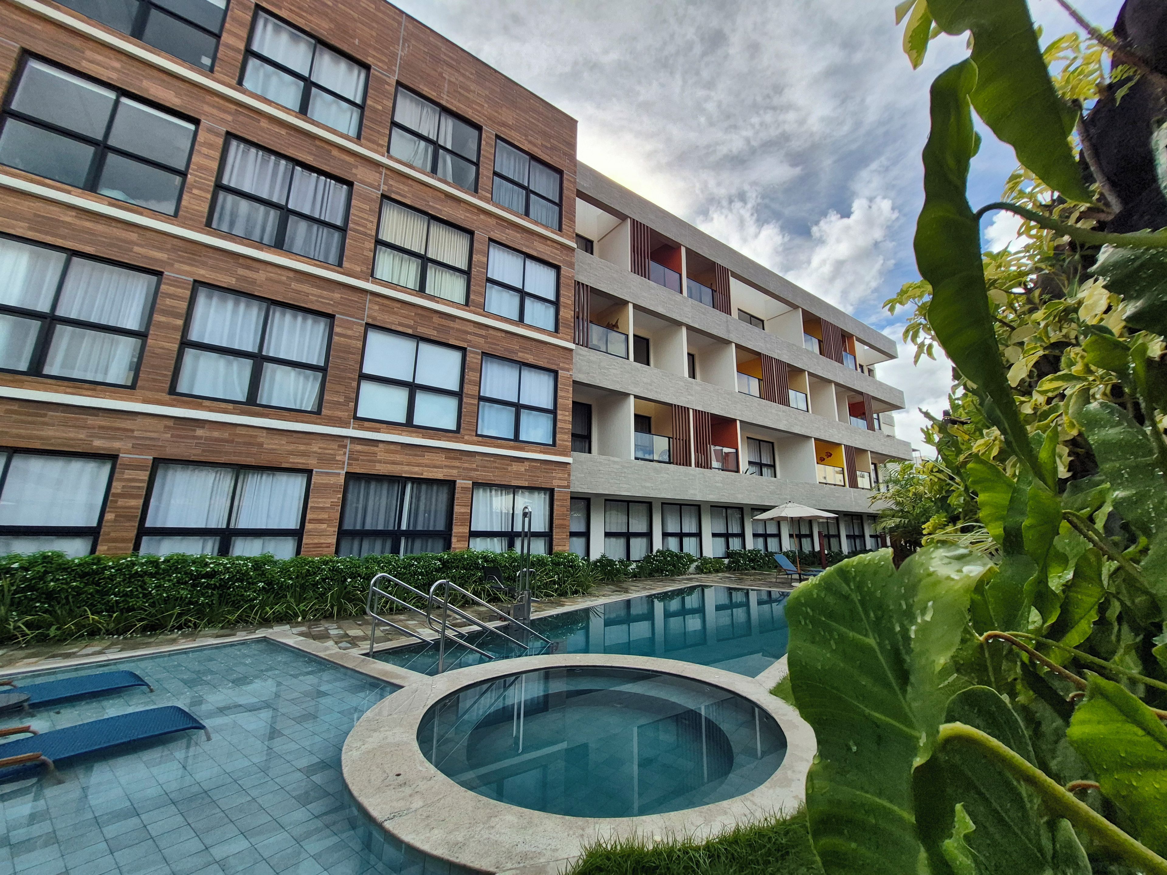 Un hôtel moderne doté d’une piscine, de nombreux balcons et d’un jardin bien entretenu.