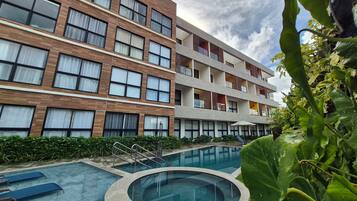 Un hôtel moderne doté d’une piscine, de nombreux balcons et d’un jardin bien entretenu.