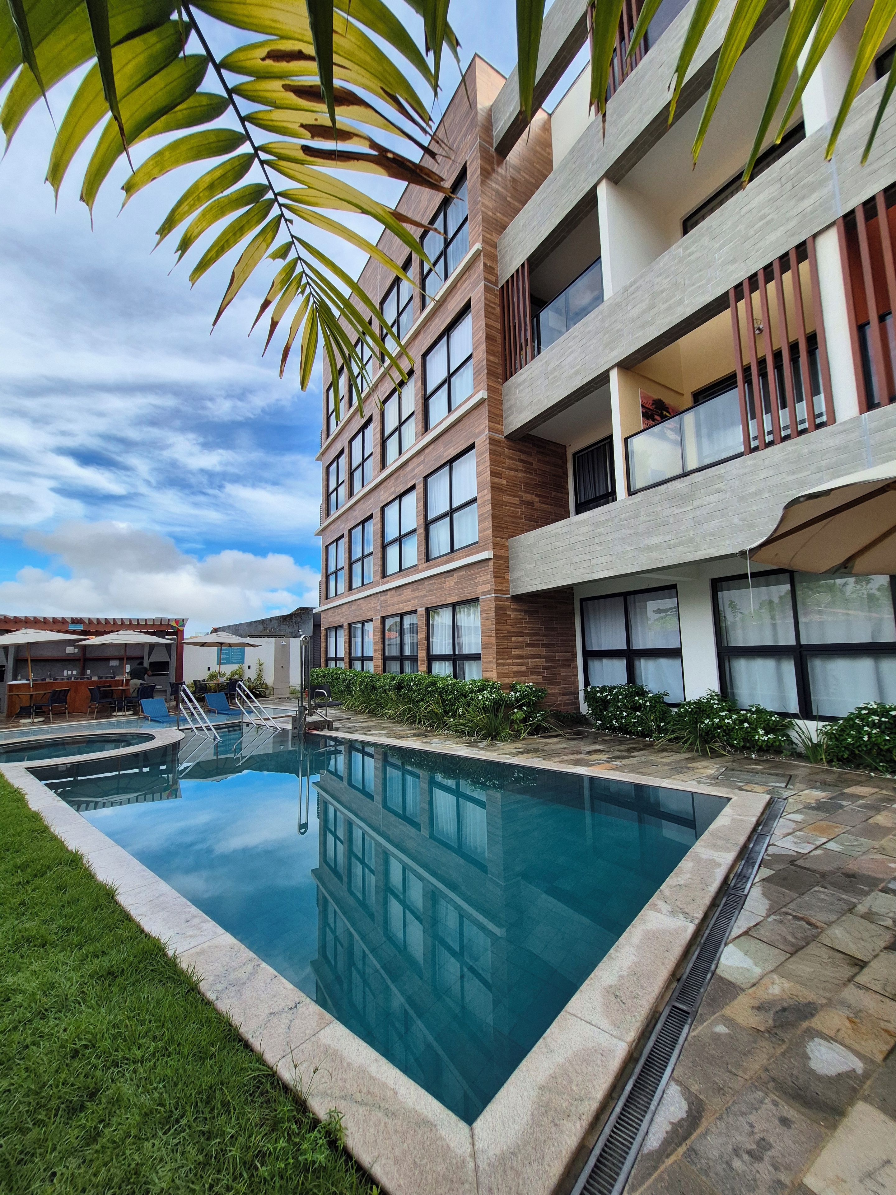 Um edifício moderno com piscina, área de estar ao ar livre e céu claro.