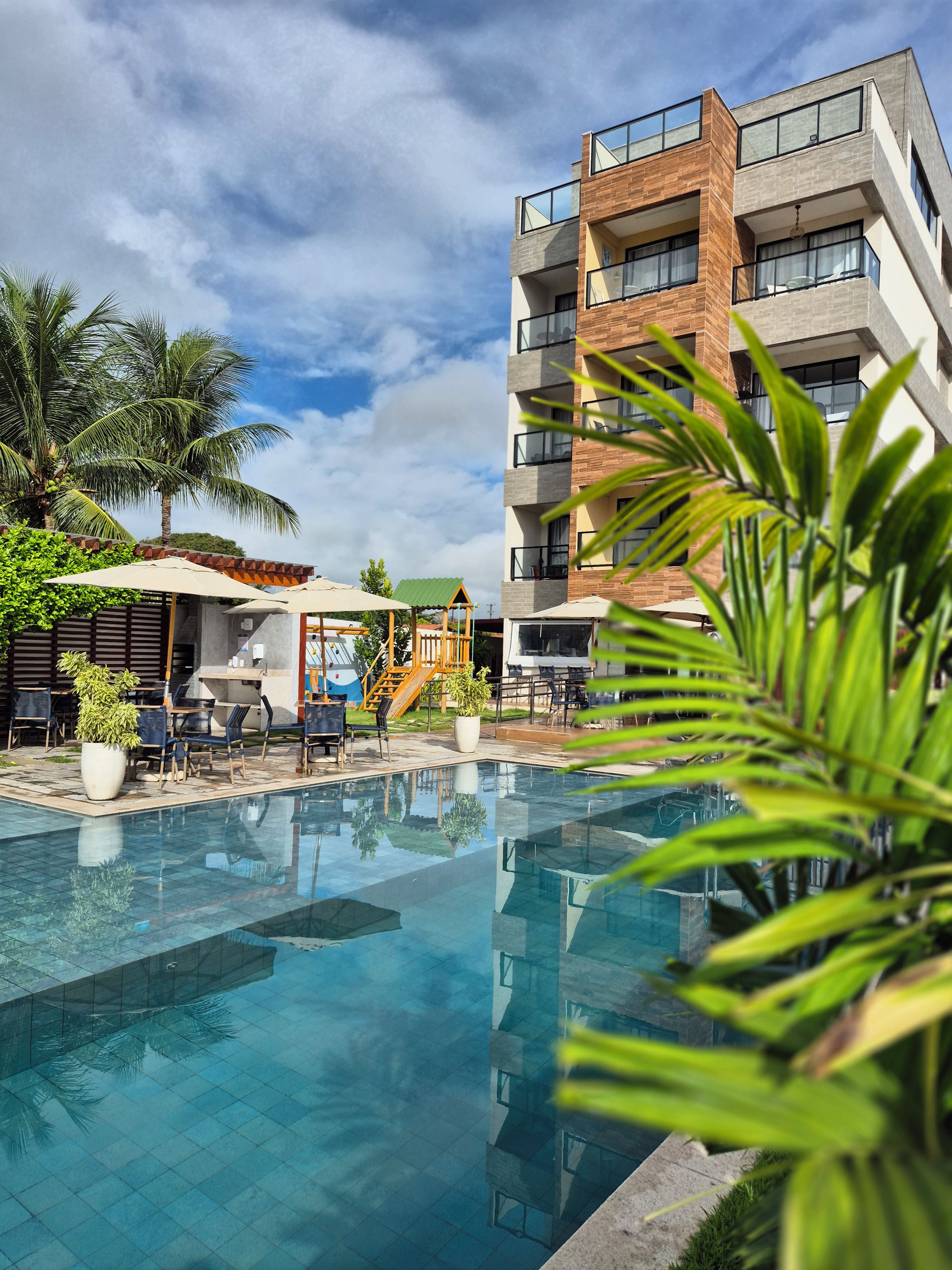 Piscina com reflexo de um edifício e palmeiras.