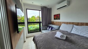 Une chambre d’hôtel avec un lit, un canapé, une fenêtre avec des rideaux, un appareil de climatisation et un tableau au mur.