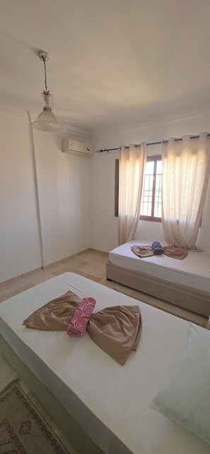 A room with a bed, a window with curtains, an air conditioning unit, and a ceiling fan. - Appartement le palmeraie de guéliz Marrakech (Marrakech)
