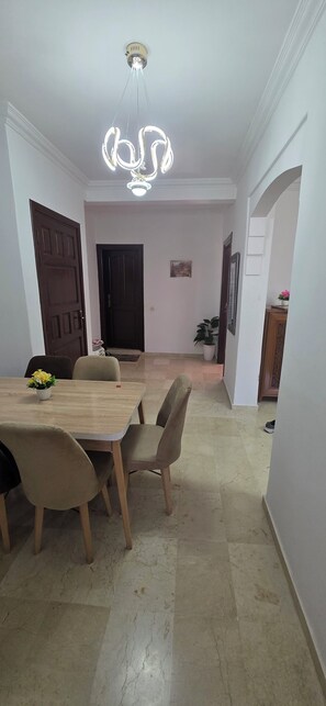 A dining area with a table and chairs, a ceiling light fixture, and a door leading to another room. - Appartement le palmeraie de guéliz Marrakech (Marrakech)