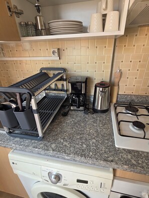 Une cuisine équipée d’une machine à café, d’une cuisinière, d’un lave-vaisselle et d’un porte-ustensiles.
