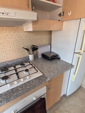 A kitchen with a gas stove, a microwave, a refrigerator, and wooden cabinets. - Appartement le palmeraie de guéliz Marrakech (Marrakech)