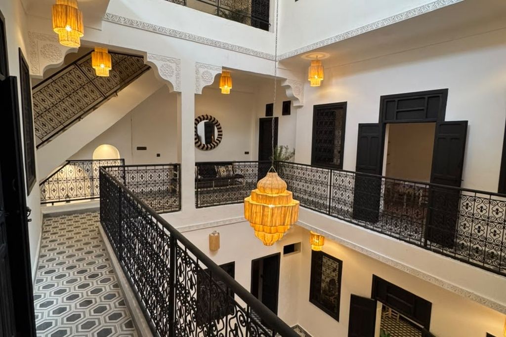 A multi-level interior with a staircase, patterned flooring, and hanging light fixtures.