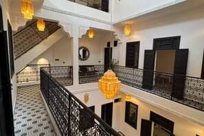A multi-level interior with a staircase, patterned flooring, and hanging light fixtures. - Riad Timizar (Marrakech)