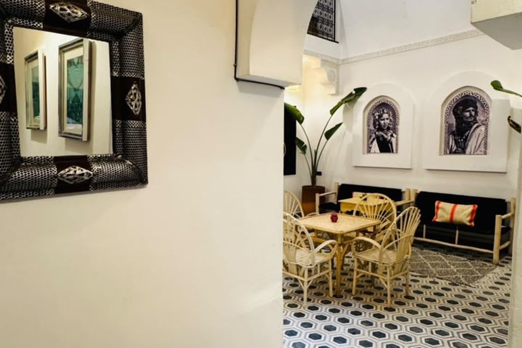 Un comedor con una mesa y sillas, piso con diseño y obras de arte colgadas en la pared.