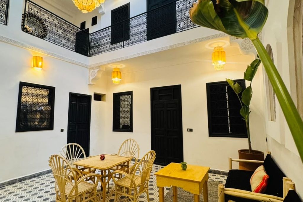 A courtyard with a dining table and chairs, a potted plant, and a staircase leading to an upper level.