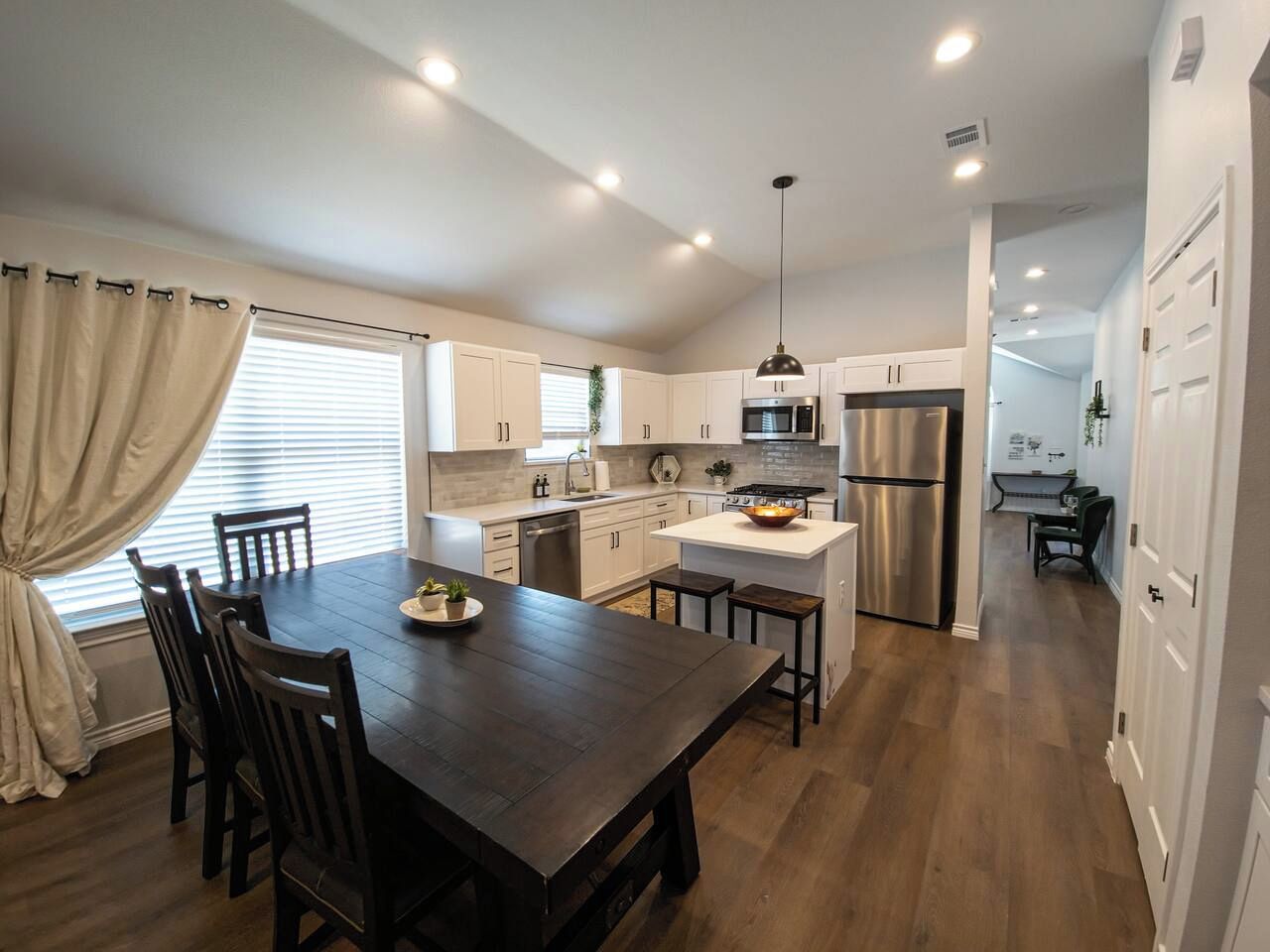 Una cocina moderna con una isla central, armarios blancos y electrodomésticos de acero inoxidable.