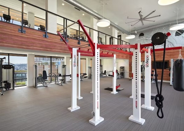 A gym with weightlifting equipment, a punching bag, and a view of the city.
