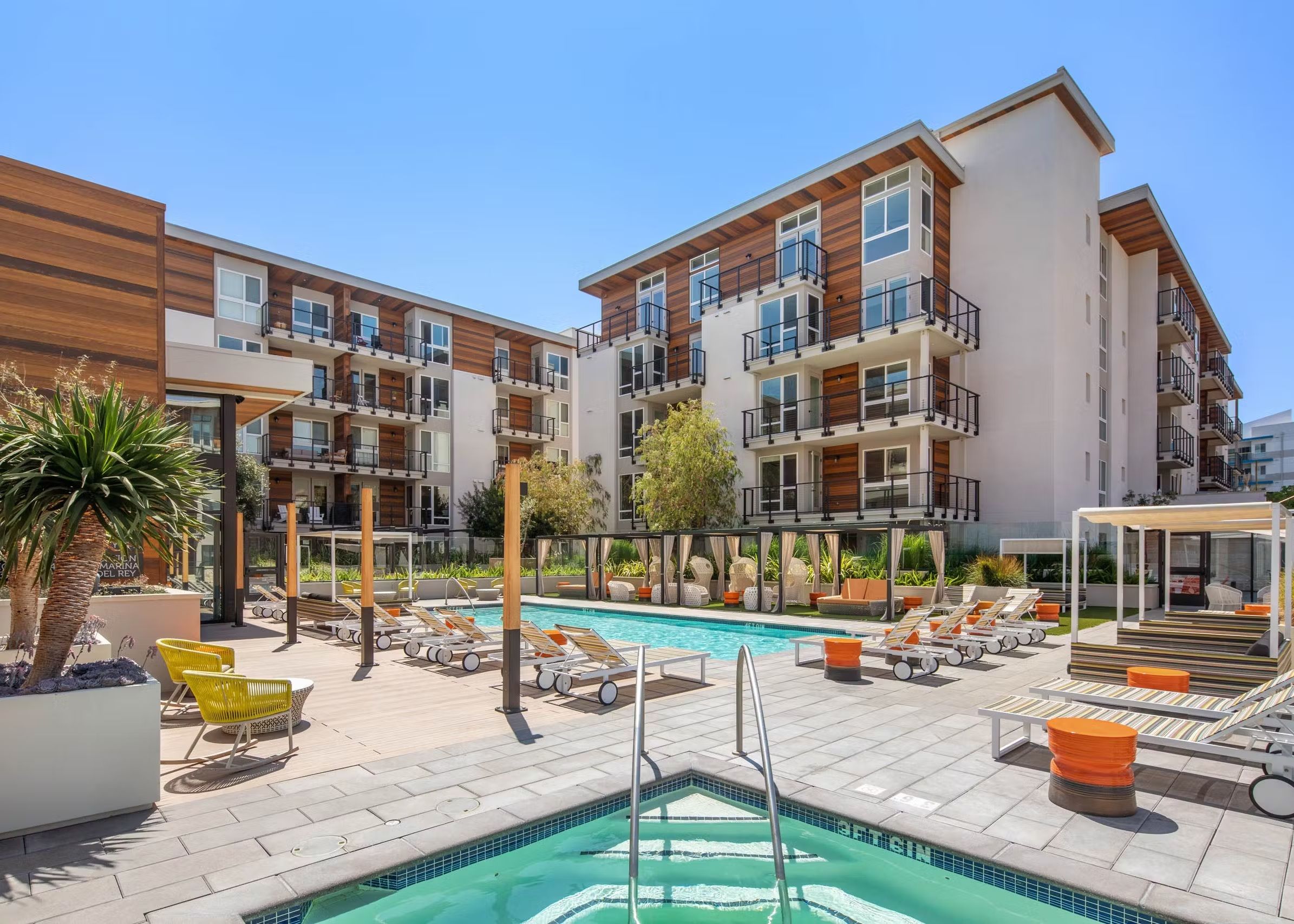 A modern hotel with a rooftop pool area, multiple balconies, and outdoor seating.