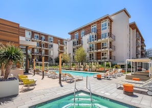 A modern hotel with a rooftop pool area, multiple balconies, and outdoor seating.