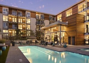 Un hotel moderno con piscina en la azotea, zona de estar al aire libre y fachada bien iluminada.