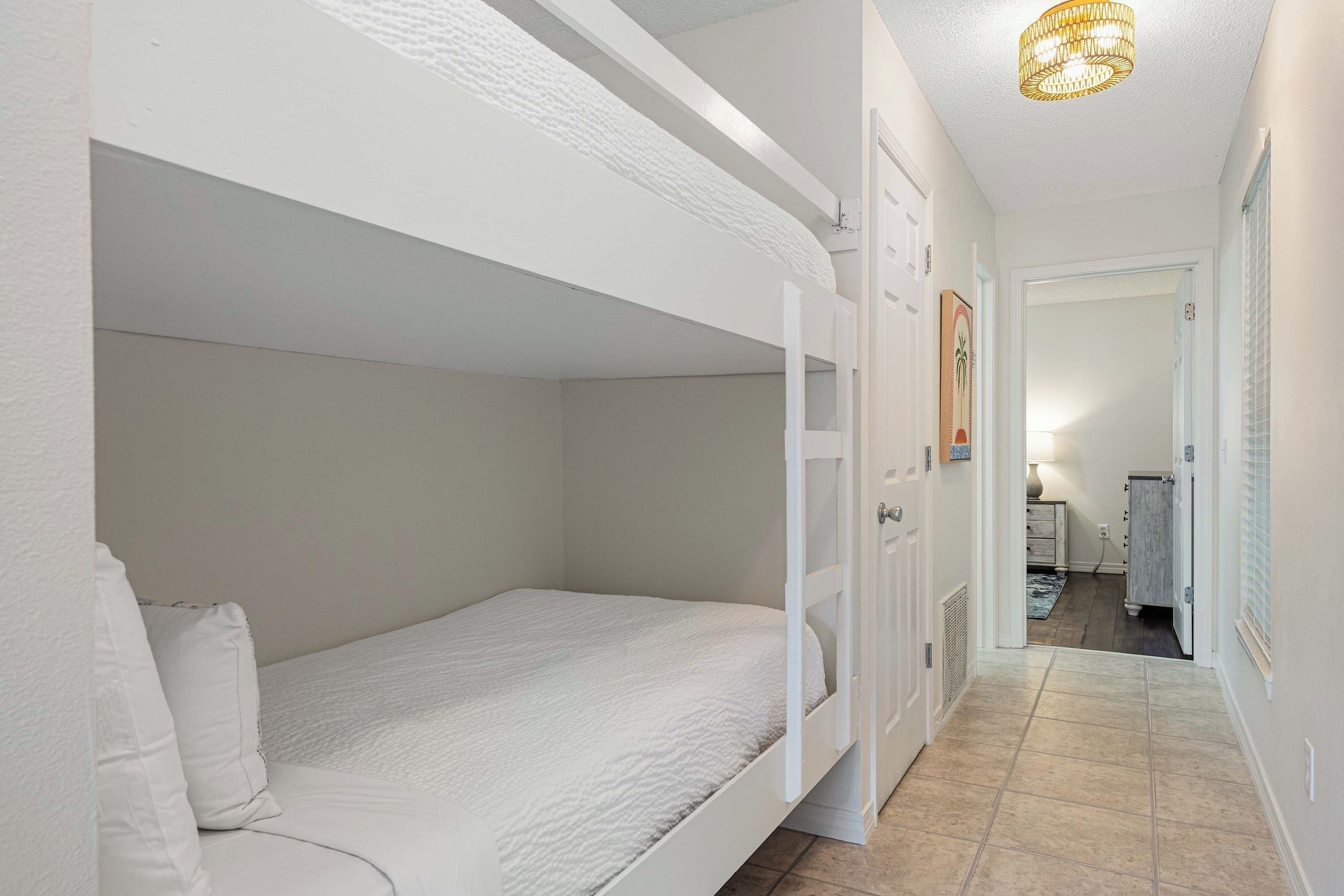 Une chambre avec des lits superposés et une porte donnant accès à une salle de bain.