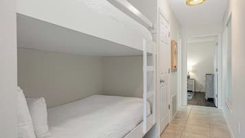 Une chambre avec des lits superposés et une porte donnant accès à une salle de bain.