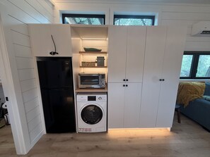 A compact kitchen with a built-in washer and dryer, a toaster, and a refrigerator.