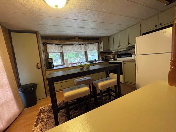 A compact kitchen with a central island, a refrigerator, and a microwave.