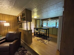 Una sala acogedora con un sillón de cuero, un mueble de entretenimiento de madera y una mesa de comedor con sillas.