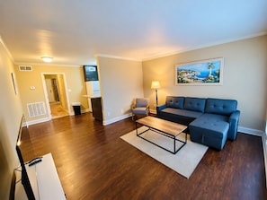 A living room with a sofa, a coffee table, a lamp, and a painting on the wall. - First-Floor Highlands Escape: Golf Course Views (Birmingham)