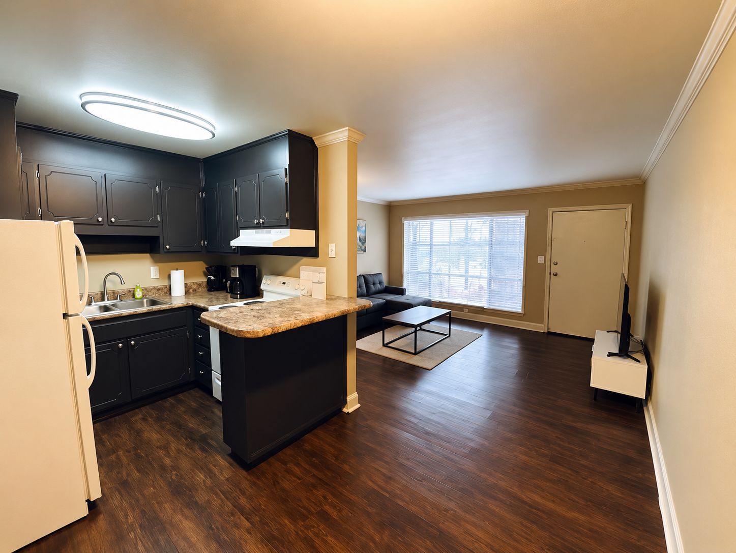 A modern kitchen with dark cabinets, a white refrigerator, and a central island.