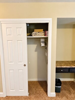 Een kamer met een gesloten deur, een vloerbedekking, een bureau met een lade en een prullenbak.