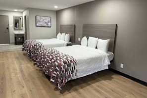 Una habitación de hotel con dos camas, un baño y un pasillo.