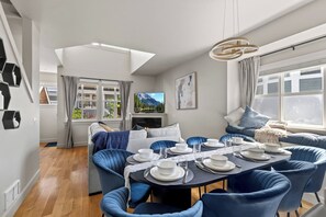 Un comedor moderno con una mesa redonda preparada para seis personas, sillas tapizadas en azul, una chimenea y una vista panorámica a través de las ventanas.