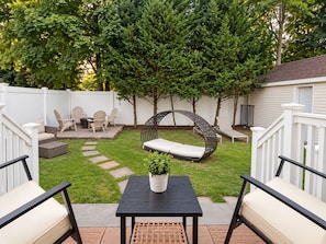 A backyard with a patio area, outdoor furniture, a swing chair, and a potted plant.