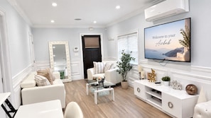 A modern living room with a sofa, coffee table, and a TV mounted on the wall.