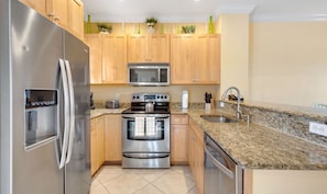 A modern kitchen with stainless steel appliances, wooden cabinets, granite countertops, and a built-in microwave. - Waterfront Villa w/ Uninterrupted Ocean Views (Marathon)