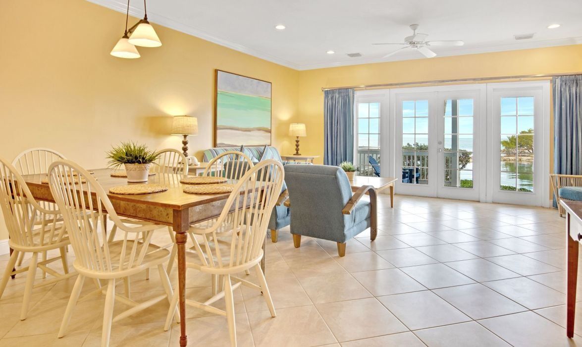 A dining area with a table and chairs, a ceiling fan, and a view through a glass door.