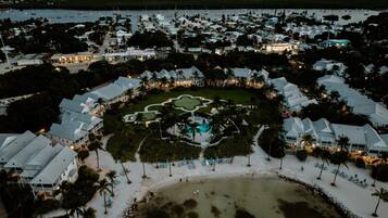 A resort with multiple buildings, a central pool area, and a beach.