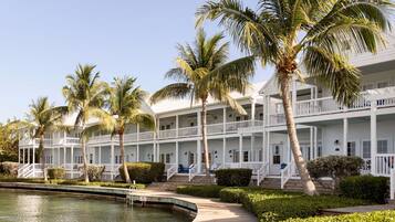 A multi-story hotel with balconies, a swimming pool, and palm trees.