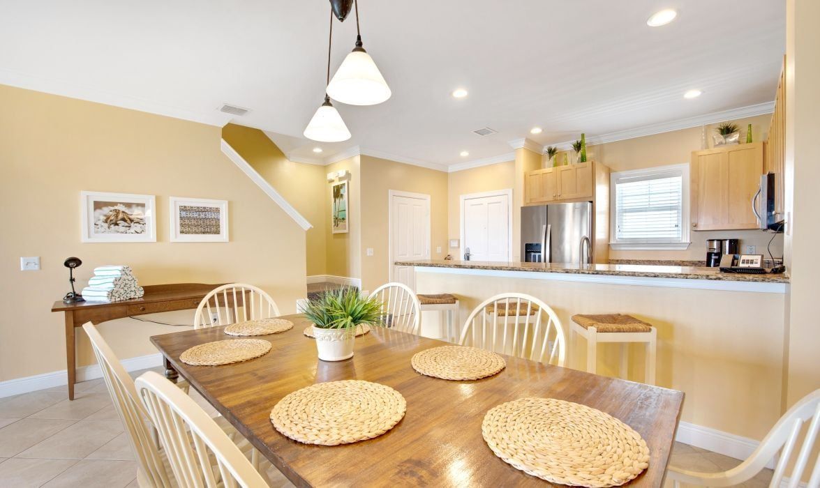A dining area with a wooden table, white chairs, and woven placemats.