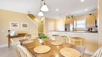 A dining area with a wooden table, white chairs, and woven placemats.