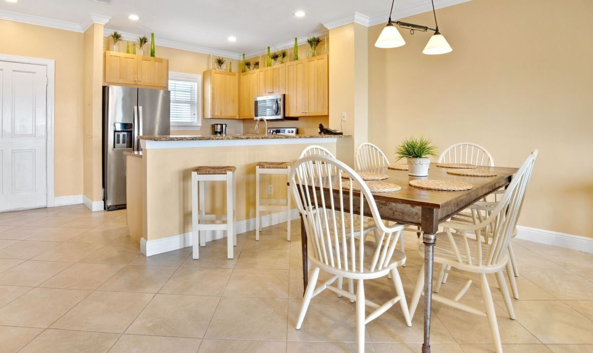 A modern kitchen with a central island, white chairs, and a dining table.