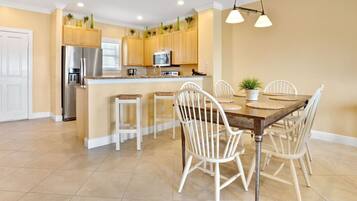 A modern kitchen with a central island, white chairs, and a dining table.