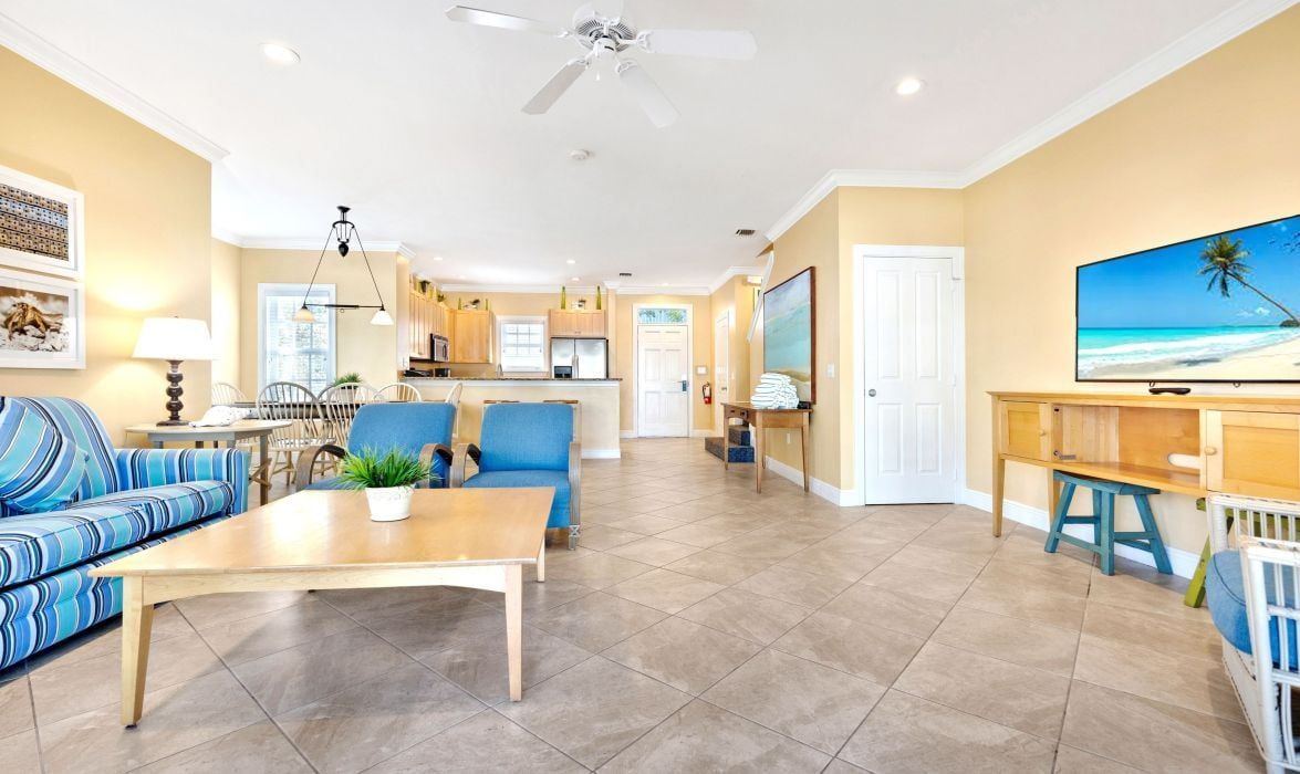 A spacious living area with a sofa, coffee table, and a television on a stand.
