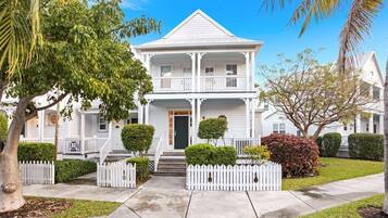 A two-story white house with a front porch, a picket fence, and a well-maintained lawn.