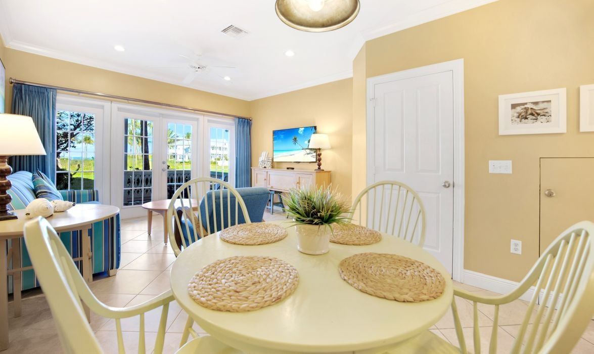 A dining area with a round table, chairs, and a potted plant.