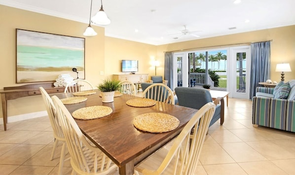 A dining area with a wooden table, woven placemats, and white chairs.