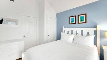 A bedroom with a white bed, a white dresser, and a blue accent wall.
