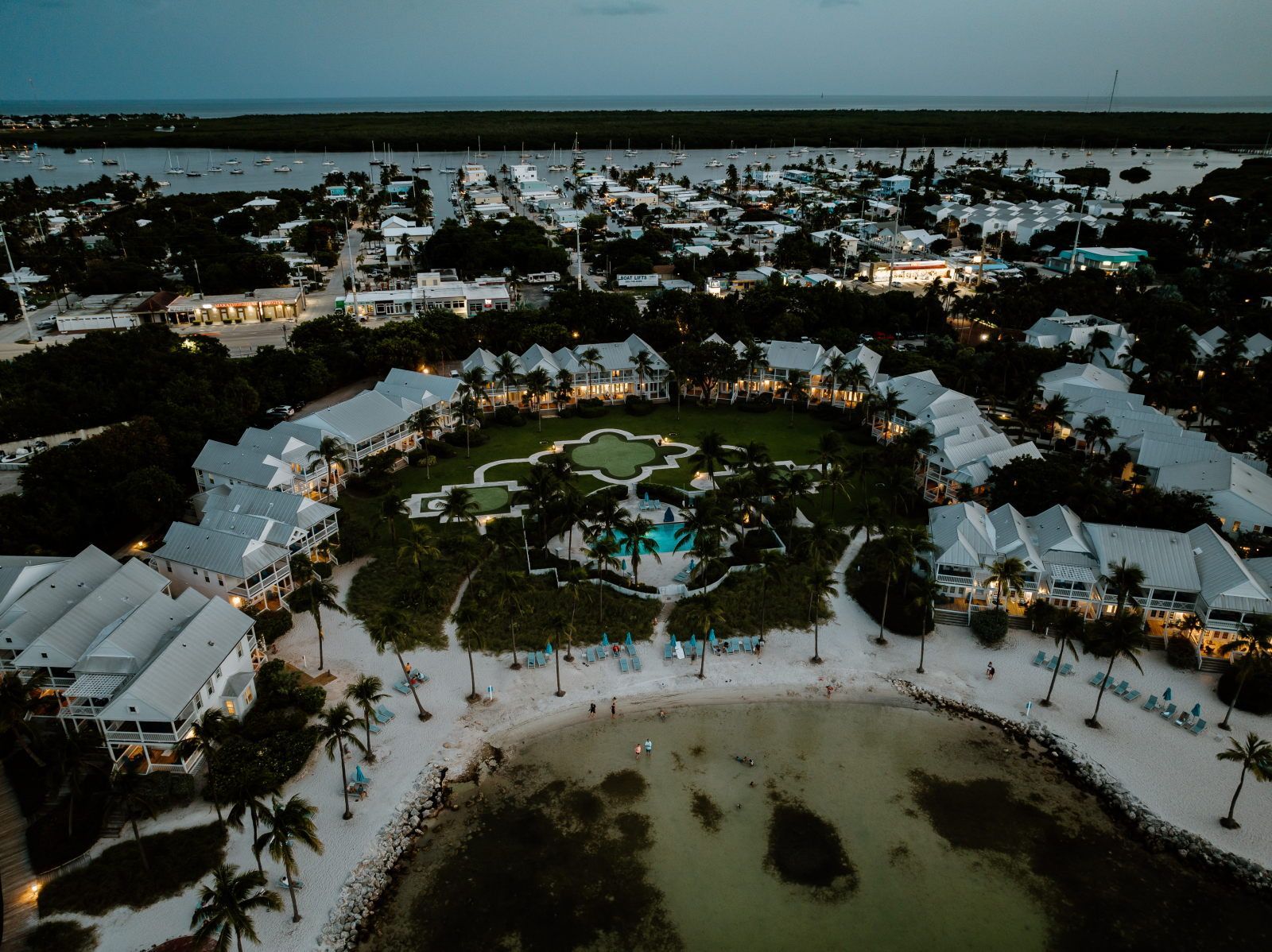 A resort with multiple buildings, a central pool area, and a beach.