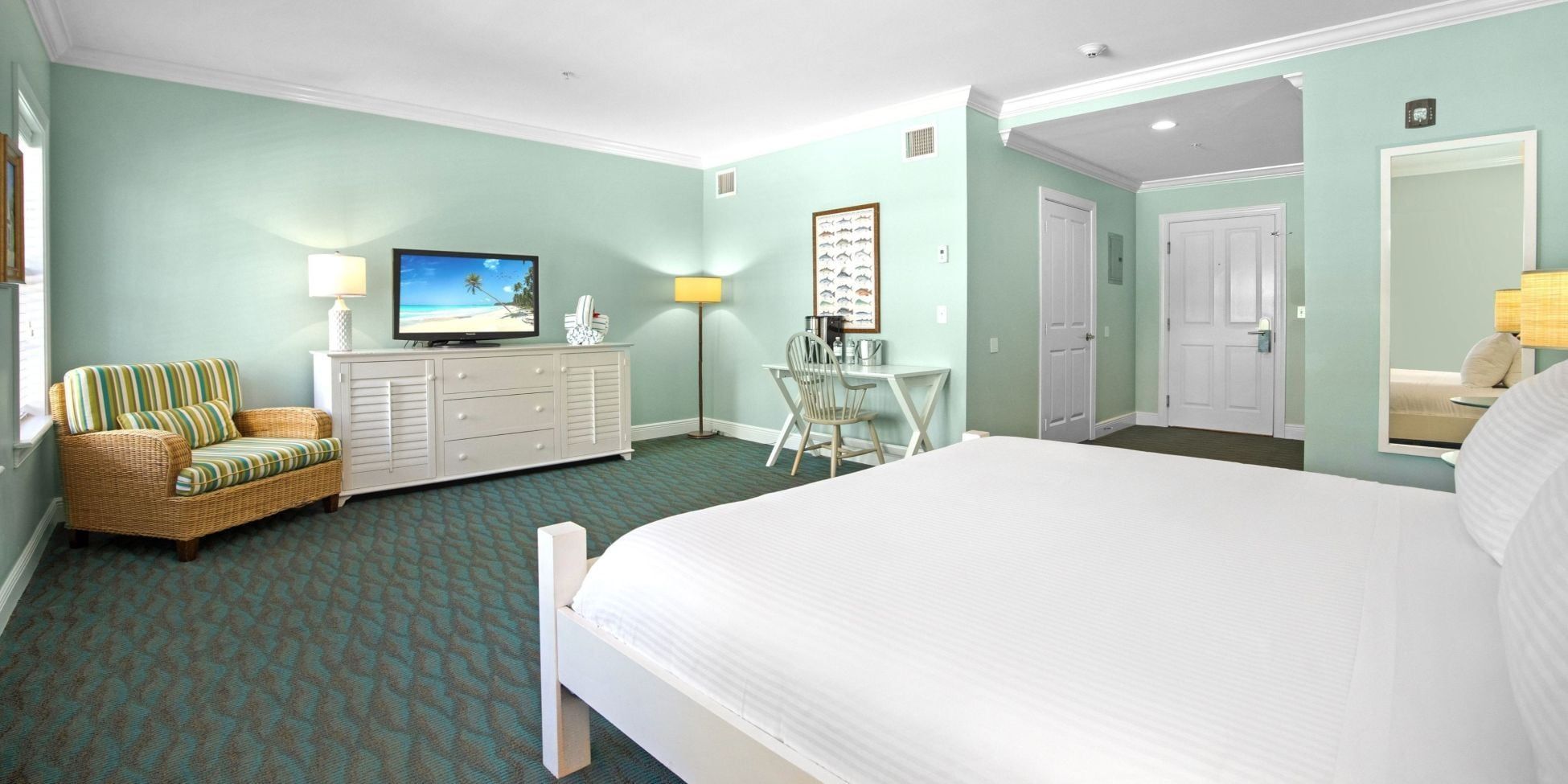 A hotel room with a bed, a television, a desk, and a chair.