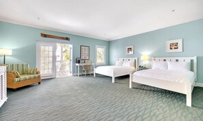 A bedroom with two beds, a chair, a desk, and a window.