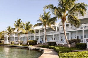 A multi-story hotel with balconies, a swimming pool, and palm trees.