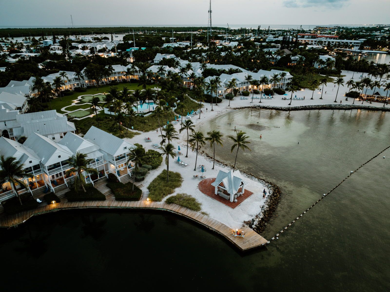 A coastal resort with multiple white buildings, a sandy beach, and a calm water body.